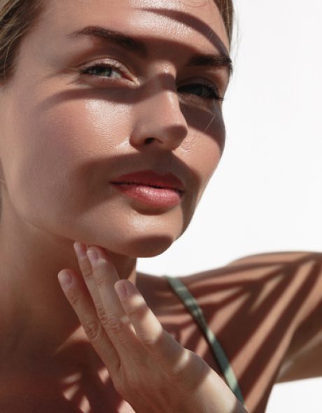 Young Woman with Shadow of Palm Leaves on White Wall.